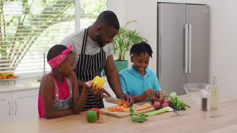 Afroamerikanischer-Vater-Und-Kinder,-Die-Zu-Hause-In-Der-Küche-Gemüse-Hacken