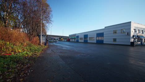 tráfico en una calle de asfalto fuera de un edificio industrial en tromsø, noruega