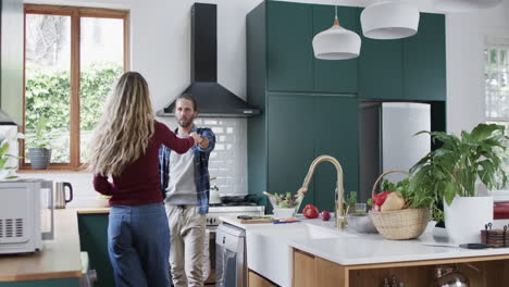 happy diverse couple dancing in kitchen at home, in slow motion, copy space