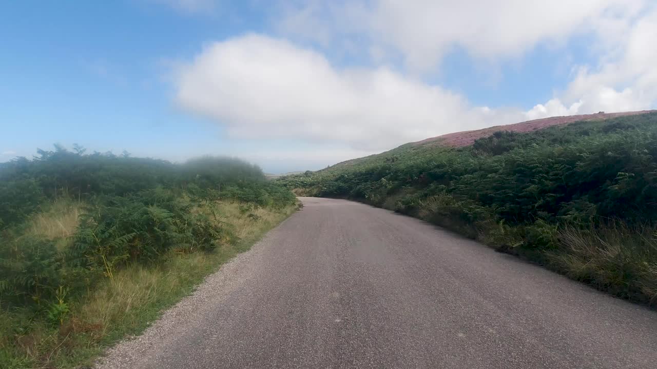 Jævn kørsel POV på landevej på solrig dag med udsigt til havet, North Devon, Storbritannien 4K