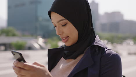 slow motion portrait of beautiful mixed race muslim woman enjoying using smartphone social media app texting in urba ncity background