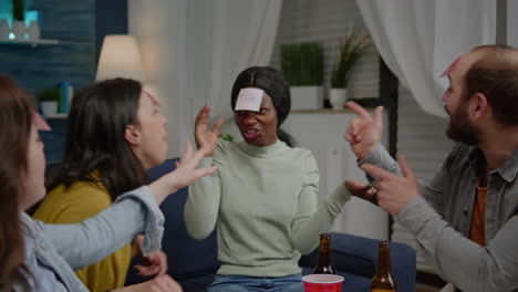 mixed race friends with sticky notes attached on forehead playing guess who game