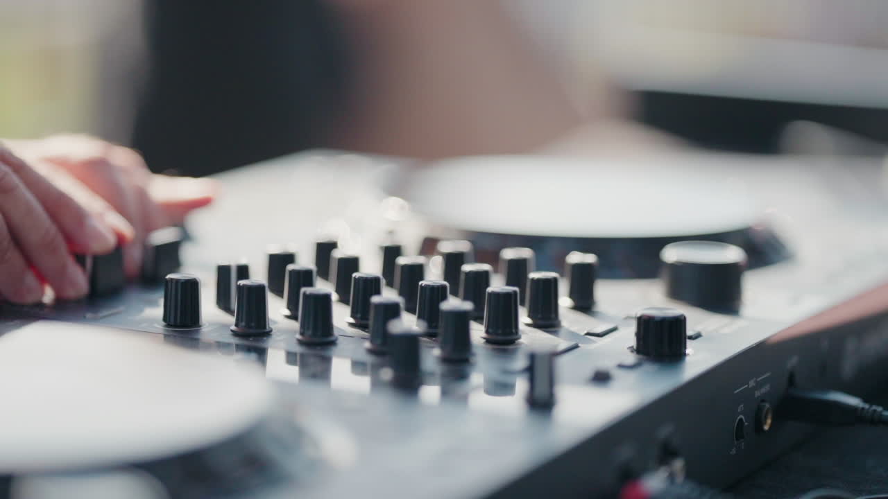 DJ's hands tweaking controls on a mixer deck