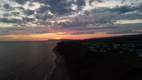 Aerial-4K-Drone-footage-of-along-the-Brightstone-Coast-on-the-Isle-of-Wight-over-a-Campsite-at-a-beautiful-Sunset