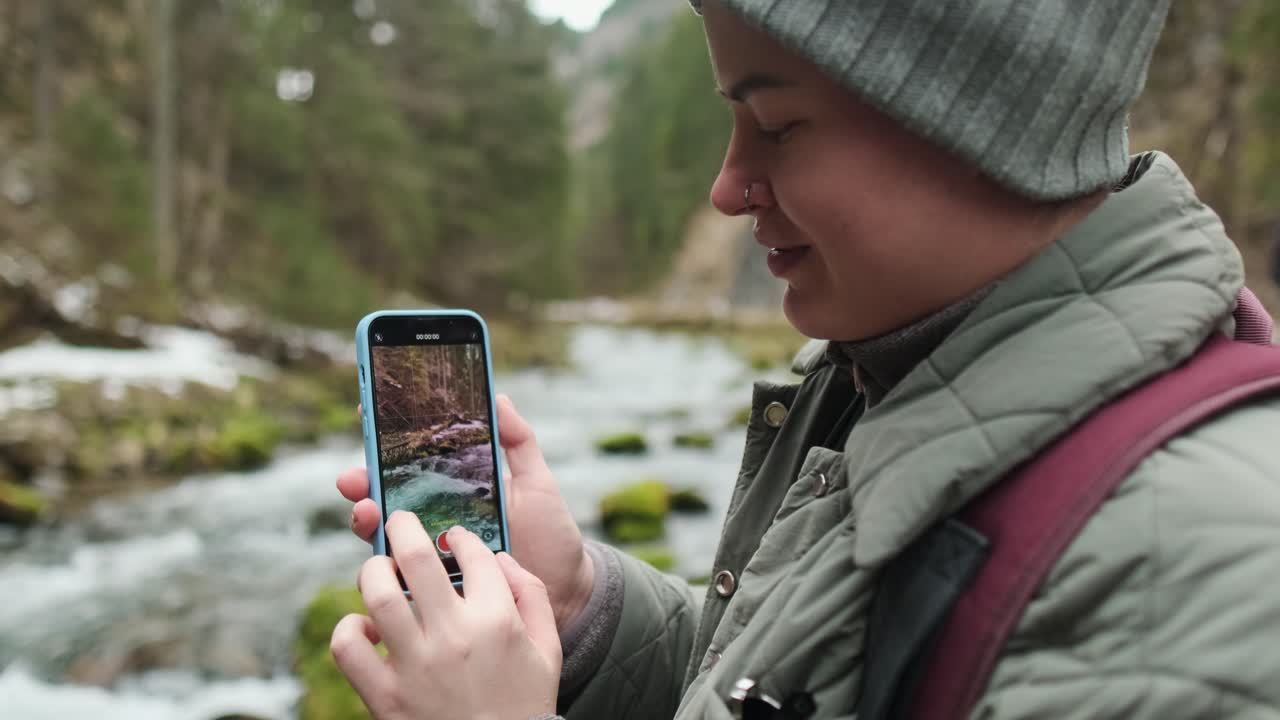 Person recording a video of a mountain stream
