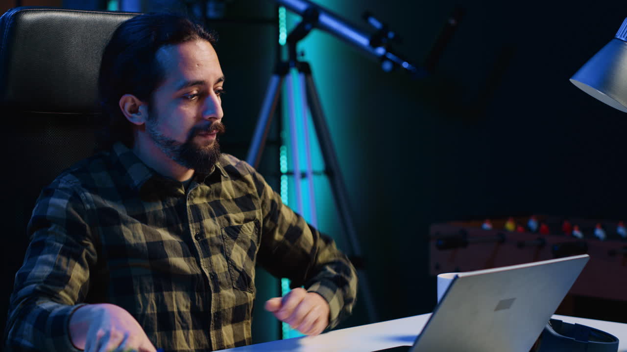 hombre recibiendo una llamada telefónica de un amigo mientras trabaja desde casa en una computadora portátil