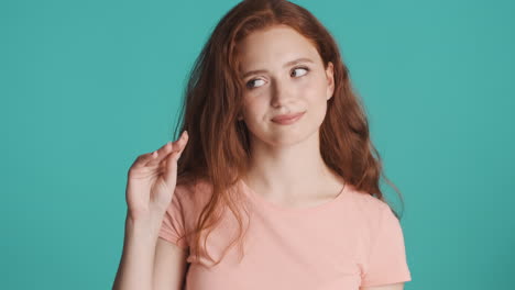 redheaded girl looking at camera on turquoise background.