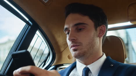 retrato de un joven hombre de negocios escribiendo un mensaje en un teléfono celular en un coche moderno.