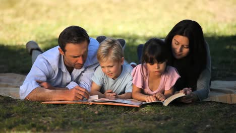 Family-reading-a-book-lying-on-a-tablecloth