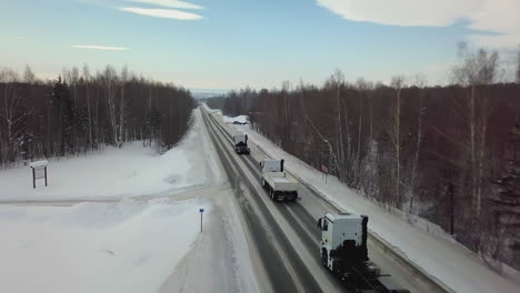 trucks on a snowy highway through a winter forest