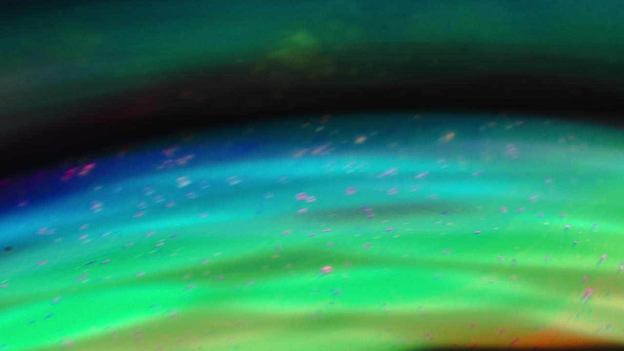Vibrant macro shot of swirling iridescent colors resembling abstract cosmic waves
