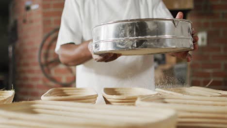 animation of midsection of african american male baker sieving flour on board