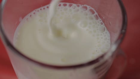 pouring milk into a glass on a red background