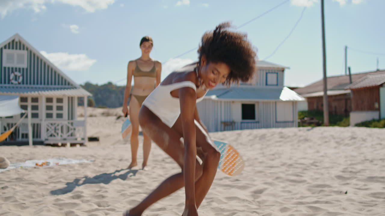 Sommerliche Mädchen spielen Tennis am Sandstrand. Fröhliches LGBT-Paar ruht sich gemeinsam aus.