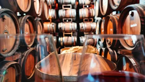 two glasses of red wine sitting on top of a wooden barrel