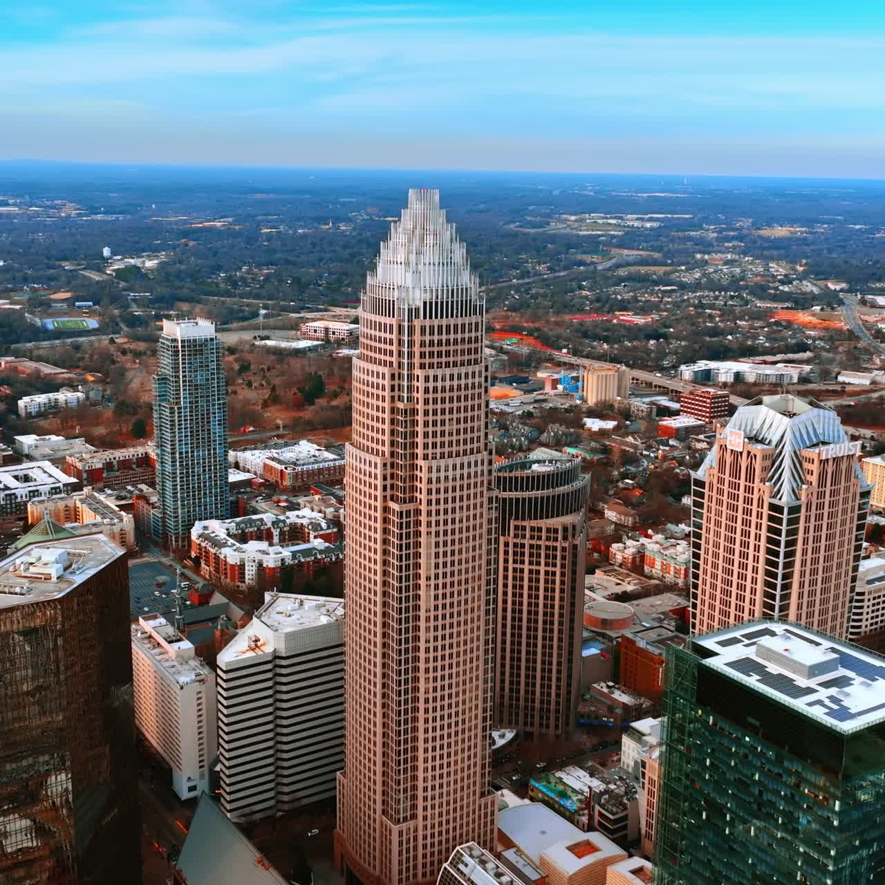 Volando più vicino al grattacielo nel centro di Charlotte, Carolina del Nord, USA. Paesaggio urbano verde con architettura a bassa altezza sullo sfondo