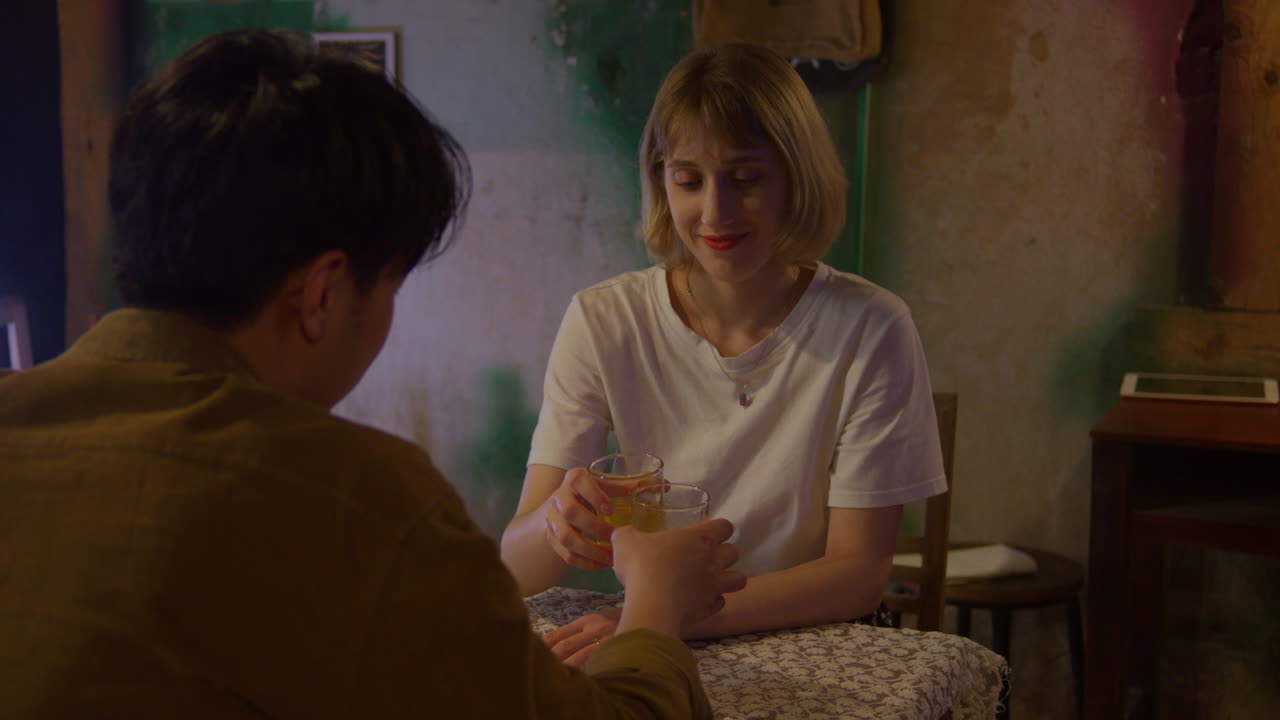 아시아인과 백인 혼혈 커플이 데이트 중에 카페 테이블 레스토랑에서 차 한 잔을 마시며 대화를 나누고 있다.