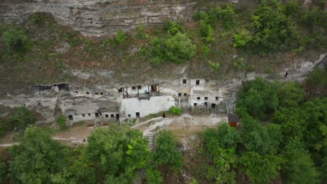 a-man-in-black-clothes-walks-along-a-mountainside-with-sharpened-holes-in-stones-the-size-of-a-human-room-in-a-dwelling-for-chiefs-monk