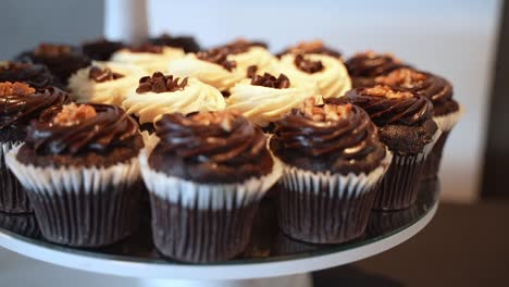 Orbiting-shot-of-attractive-chocolate-cupcakes-on-a-cake-stand,-with-a-blurry-background