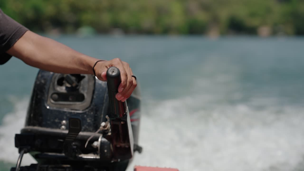 Close-up of a man's hand gripping a boat motor handle while navigating across Lake Petén Itzá, Guatemala.