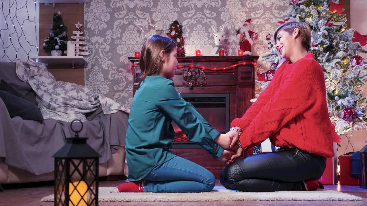 Mother and Daughter Celebrating Christmas by the Fireplace