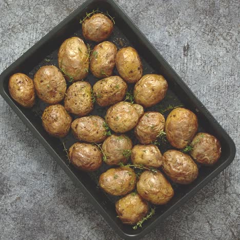 Oven-baked-whole-potatoes-with-seasoning-and-herbs-in-metalic-tray--Roasted-potatoes-in-jackets-