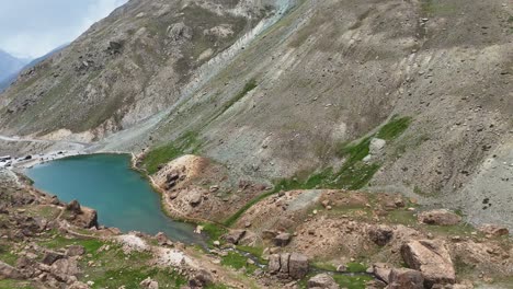 aerial drone shot showcasing the crystal-clear lake of depak tal surrounded by rocky terrain.