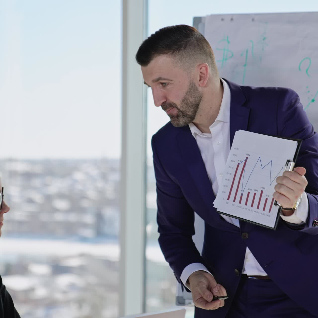 Bearded businessman holding a paper with chart and showing to female employee. Addressed lady is upset about the information