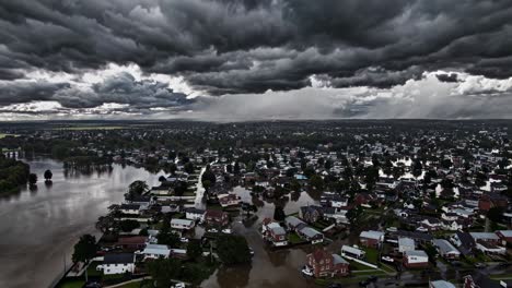 Menacing storm clouds looming over waterlogged suburban landscape, heavy rainfall saturating flooded streets and submerged residential properties