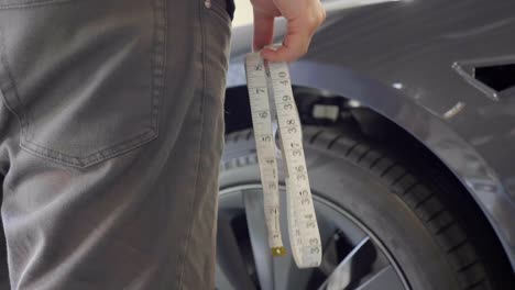 garage workshop worker holding measuring tape near car