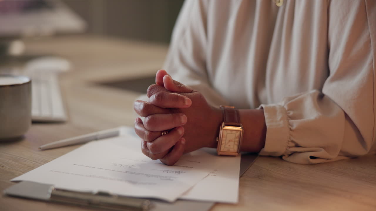 Woman with hands clasped at desk