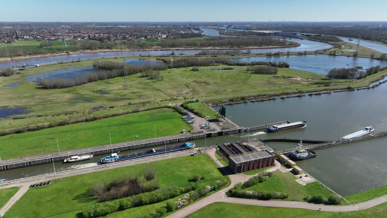Semi orbit aerial shot of Antwerp canal lock with multiple ships navigating through waterways and countryside landscape under blue sky