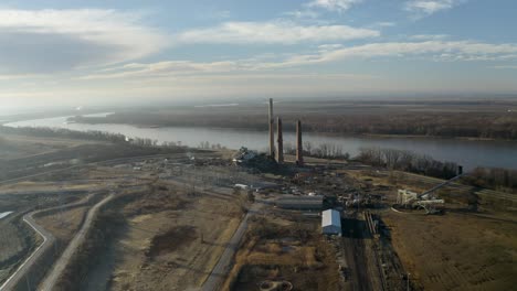 drone shot panning around smoke stacks next to the mississippi with a demolished coal power plant