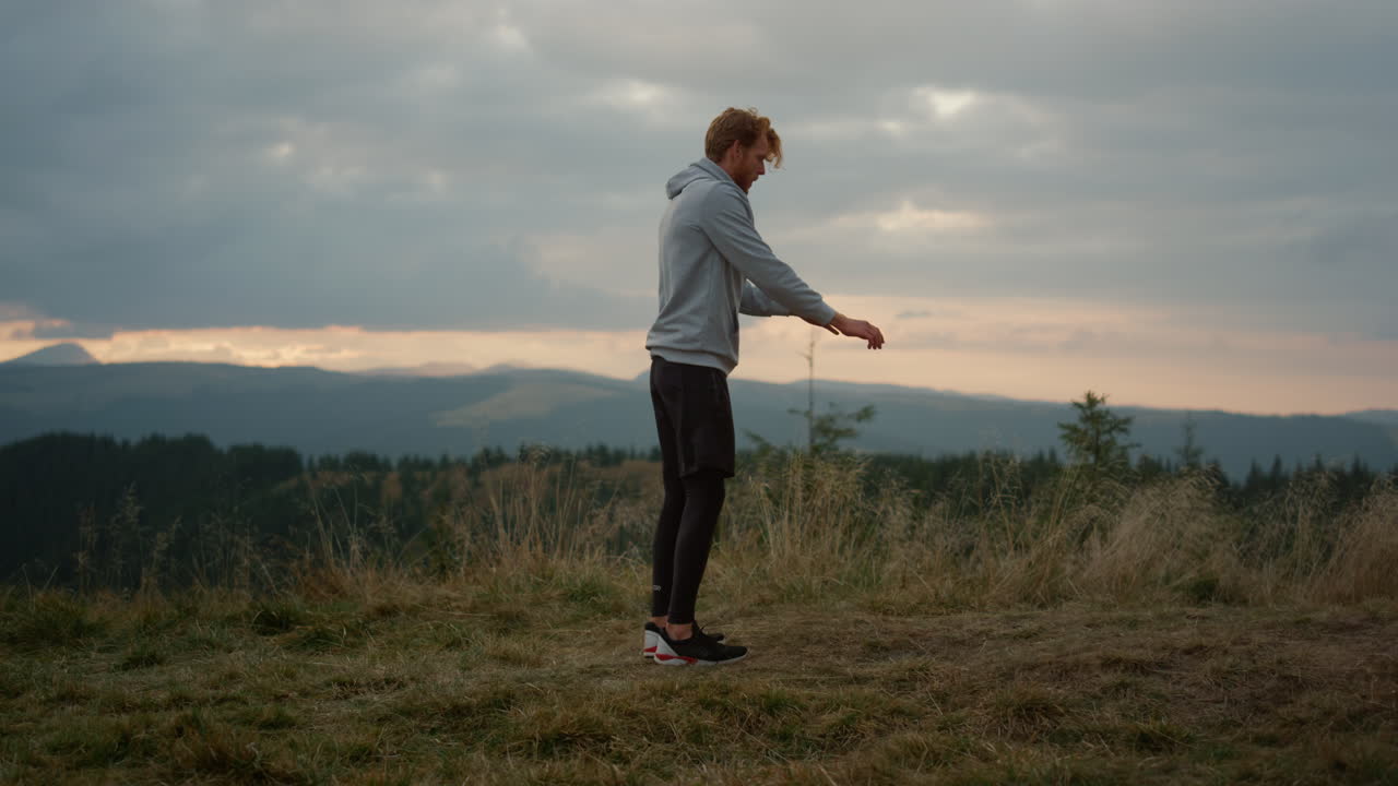 парень делает флип на месте в горах. мужчина-спортсмен выполняет сальто