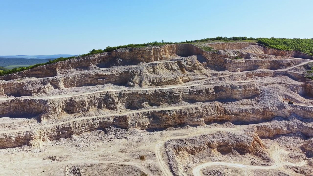 Dağlık Bölgede, Açık Havada Madencilik Operasyonlarında Kullanılan Ekipman ve Kamyon Yollarının Belirgin Olduğu, Kaya ve Toprak Katmanlarını Gösteren Taş Ocağı