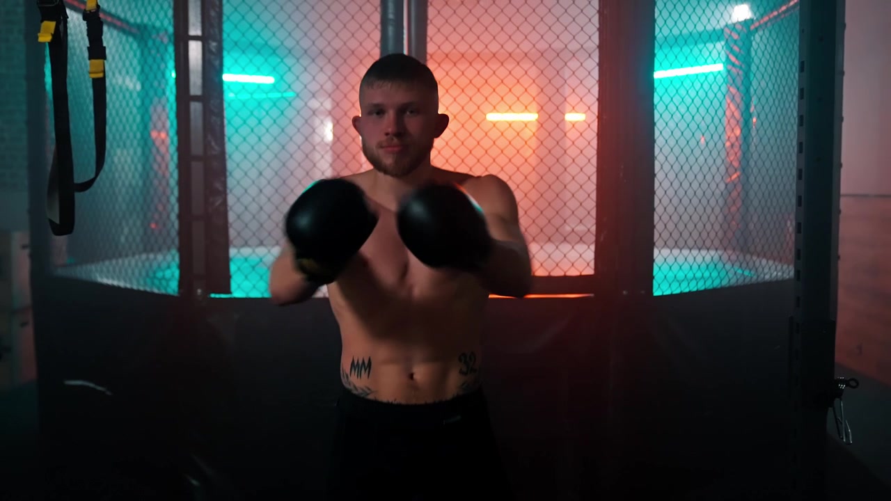 Muscular Man in Boxing Gloves Training in a Neon-Lit Gym