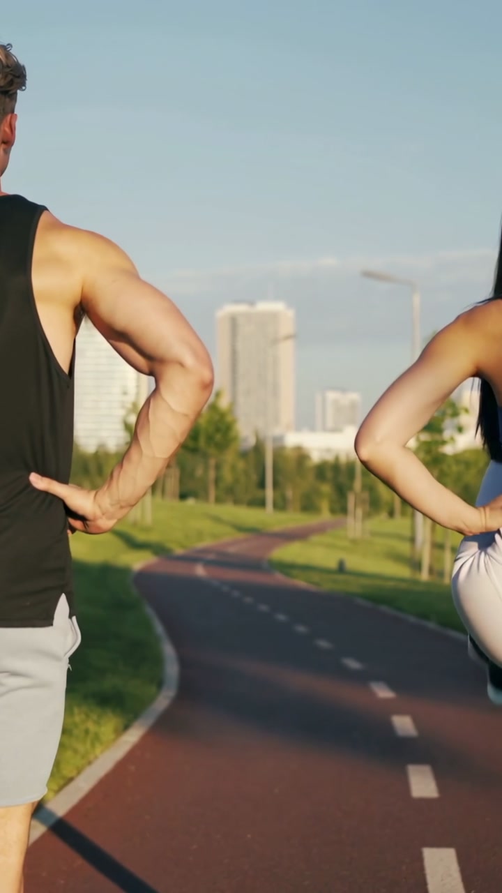 Vertical video: Warming after knee lift two runners jogging on red path for fitness in gymwear