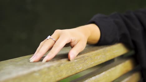 close up of a model hand wearing diamond ring moving her fingers relaxing on bench waiting no patience not interested moving shot slow motion isolated