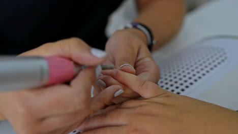 crop nail artist removing nail polish of customer in salon