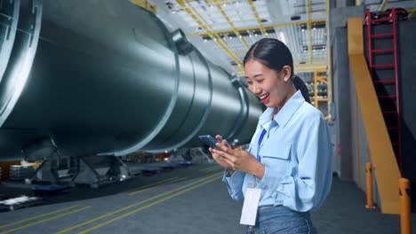 side view of asian business woman using mobile phone in pipe manufacturing factory