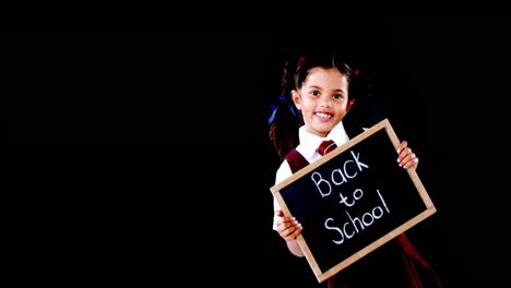 Schoolgirl-holding-slate-with-text-against-black-background
