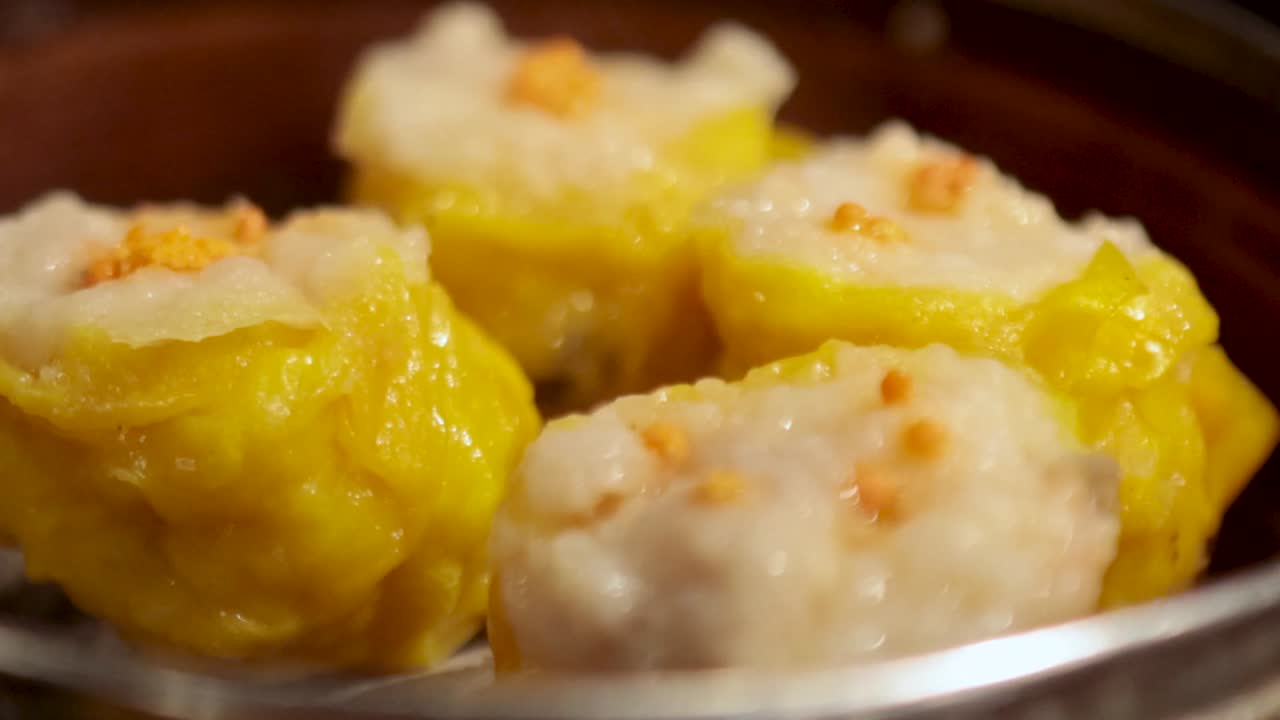 A detailed view of yellow and white steamed dumplings arranged in a bamboo basket.