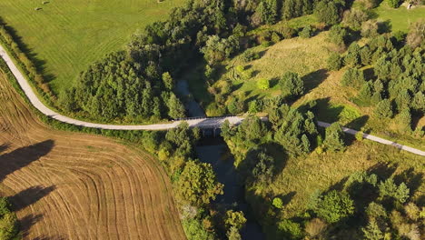 paved road with tebra river in kurzeme municipality of courland, latvia. aerial drone shot
