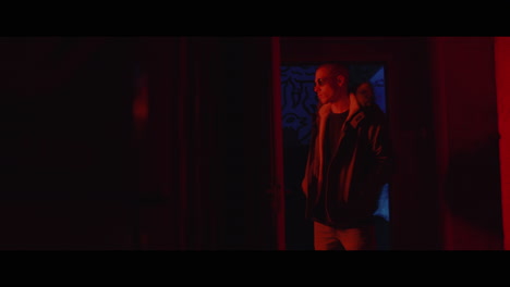 man in a jacket in a red lit urban setting