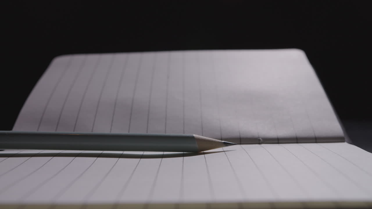Close up of a pencil being slammed down on an open notebook