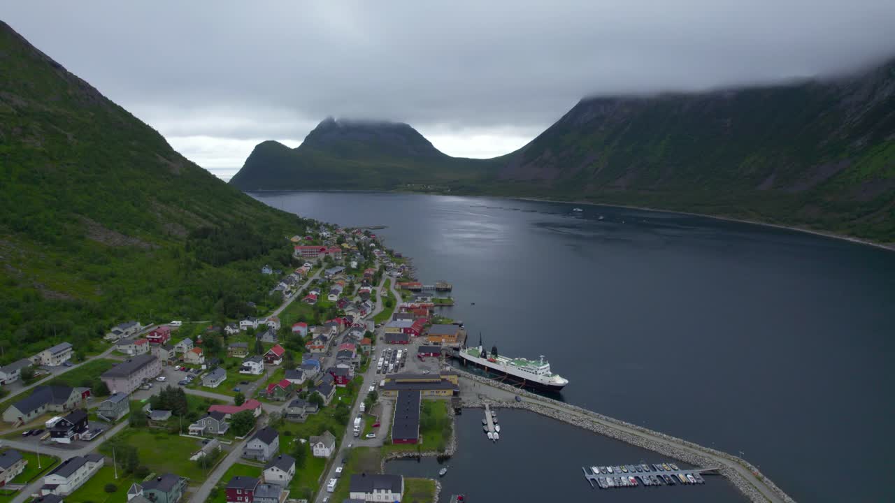 Långa bilköer som väntar på att komma ombord på färjan under sommaren i Gryllefjord, med låga moln hängande runt bergen.