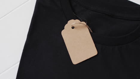 video van een platte lay van zwart t-shirt met tag en kopieerruimte op witte achtergrond