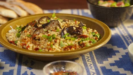 putting bulgur with eggplant close-up, vegetable salad on background. traditional middle eastern culture. delicious rice with meat. arabian cuisine. homemade food concept