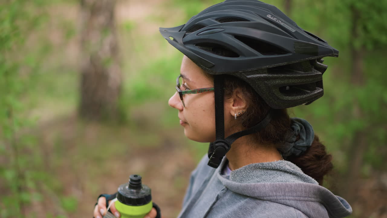 Bicycle Rider Drinking, Cyclist Taking Drink On Nature Trail, Bicyclist Pauses To Hydrate Amid Lush Green Surroundings, Cyclist On Leafy Path Takes Quick Drink From Green Bottle During Break