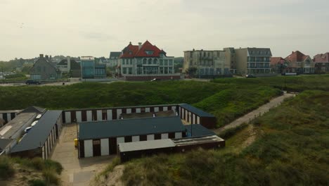 A-storage-for-surf-equipment-in-the-dunes-of-Noordwijk,-drone-shot